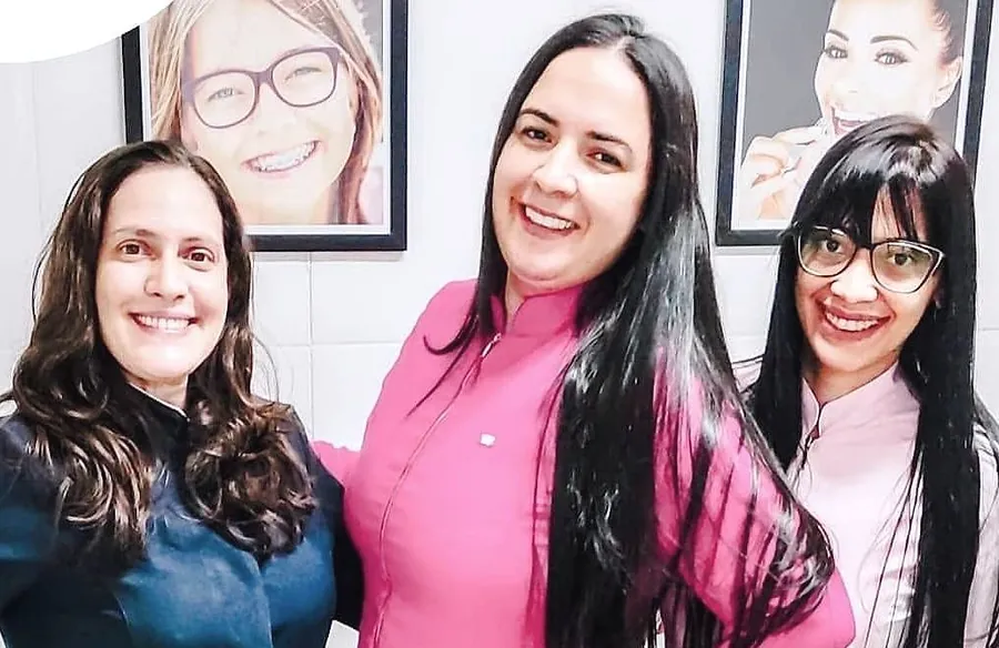 Três integrantes da equipe da Clínica Riso, sorrindo no consultório