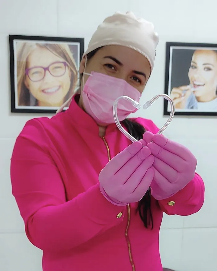 Dra. Andressa de jaleco rosa, no consultório