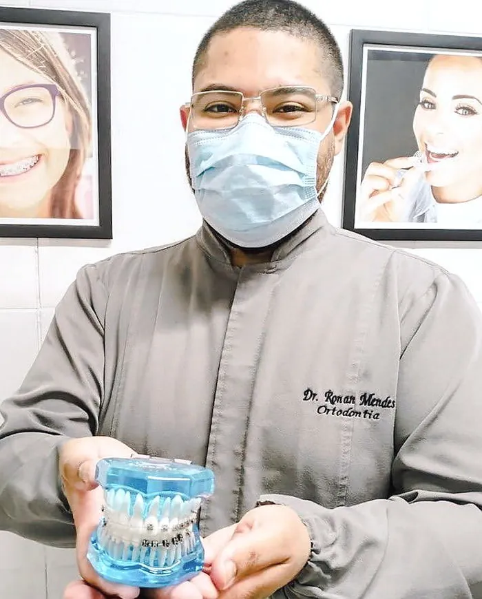 Dr. Ronan segurando um modelo de arcada com aparelho