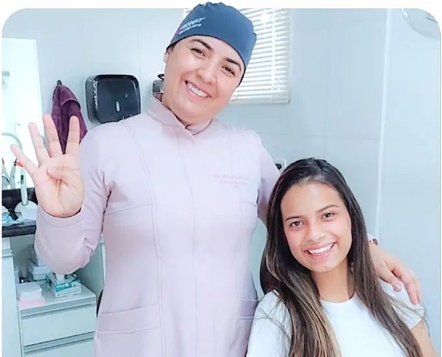 Paciente sorridente ao lado da dentista depois de tirar os sisos