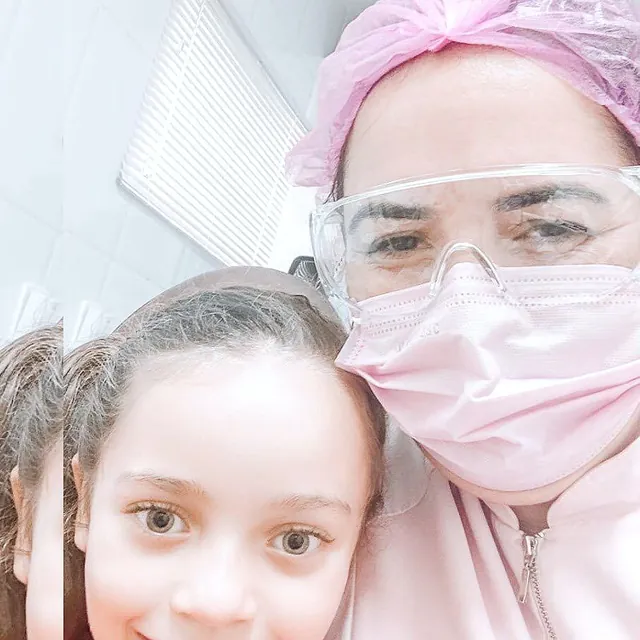 Menina sorrindo ao lado da dentista no consultório