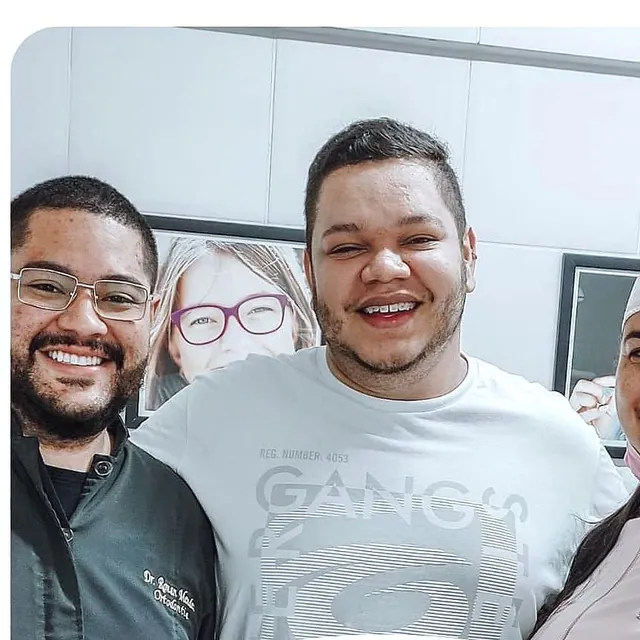 Paciente sorrindo no dia da instalação do aparelho, ao lado do ortodontista